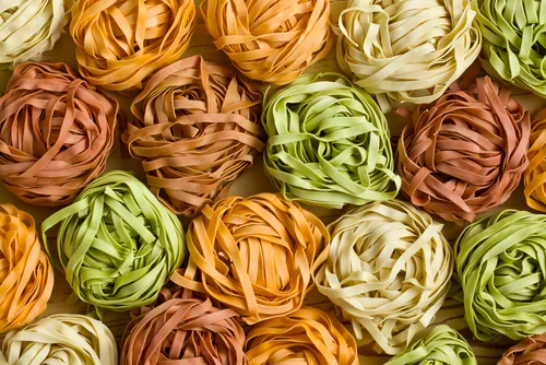 Na imagem, há vários rolos de macarrão colorido em formato de ninho
