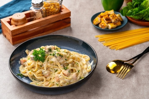 Na imagem, há um prato de macarrão com requeijão em cima de mesa